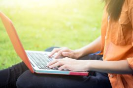 Young woman using computer on green glasses in the park. Education learning or freelance working outdoor or relaxation concept idea background.