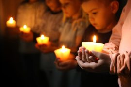 Little children holding burning candles in darkness