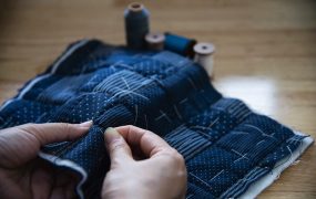 Vintage woman sewing cloth by hand with embroidery set on wooden table background - people and handmade diy housework concept